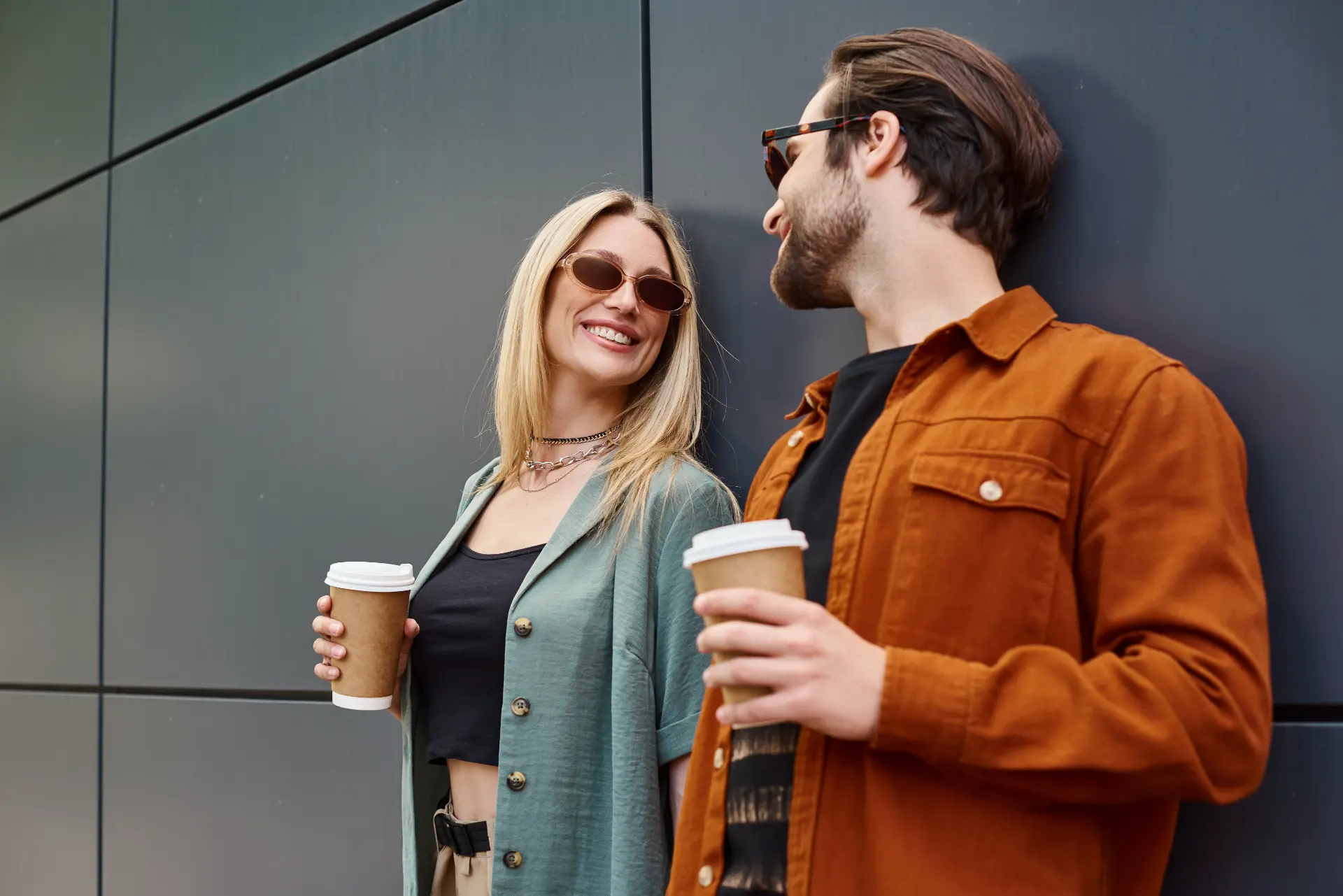 Couple laughing together outdoors with coffee