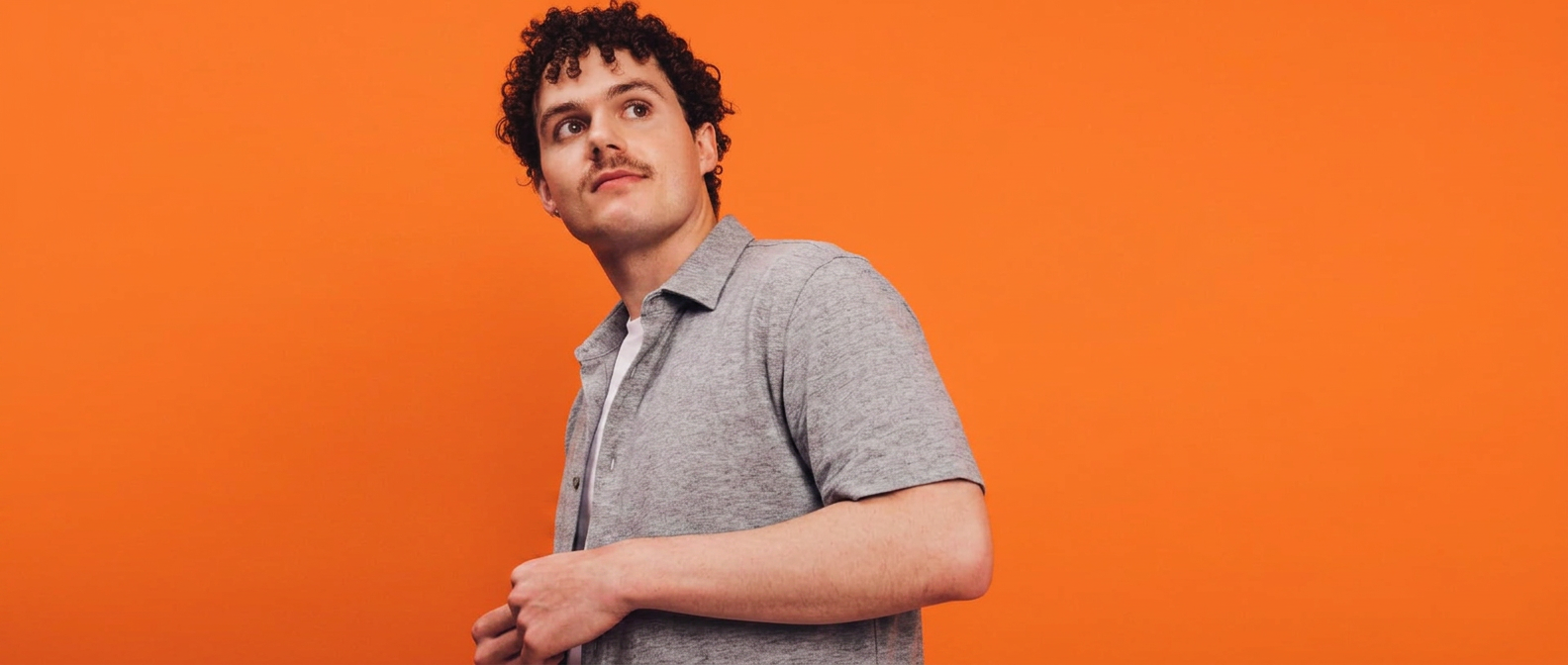 Man in a solid grey shirt against a bright backdrop